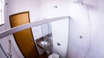A bathroom with a glass partition, a wooden door, a marble sink, and a white toilet.