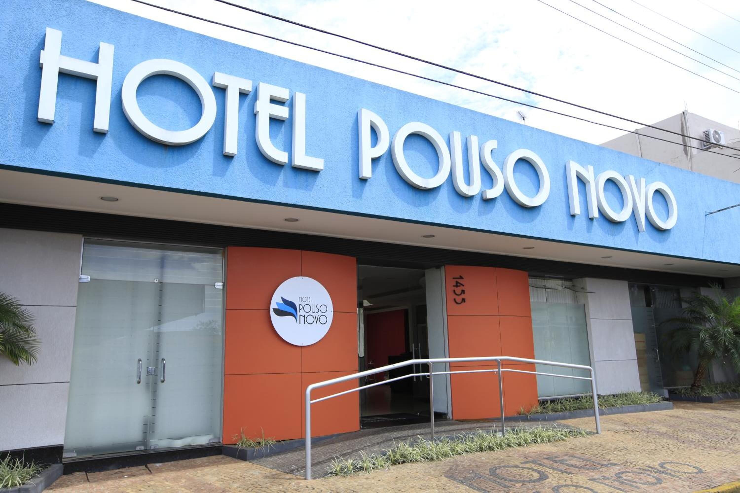A hotel named "HOTEL POUSO NOVO" with a modern facade, large glass doors, and a visible entrance ramp.