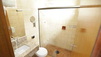 Un baño con lavamanos, inodoro y cabina de ducha con mampara de vidrio.