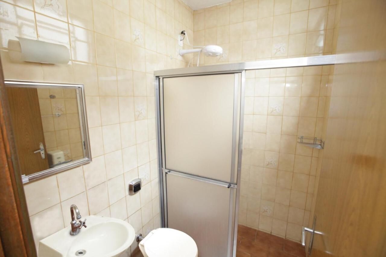 A bathroom with a shower, toilet, sink, and a mirror.