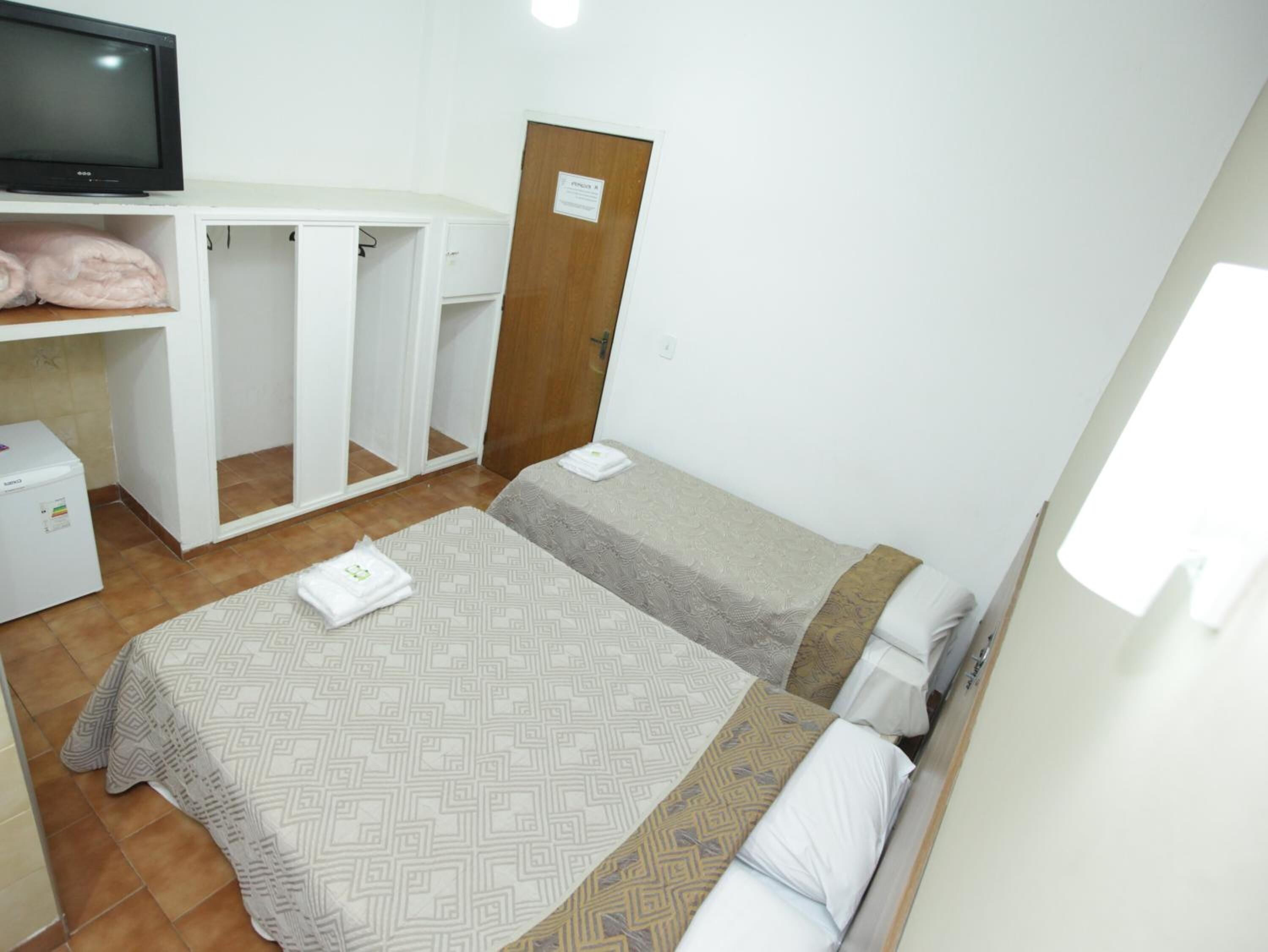 A hotel room with two beds, a TV, a wardrobe, and a washing machine.