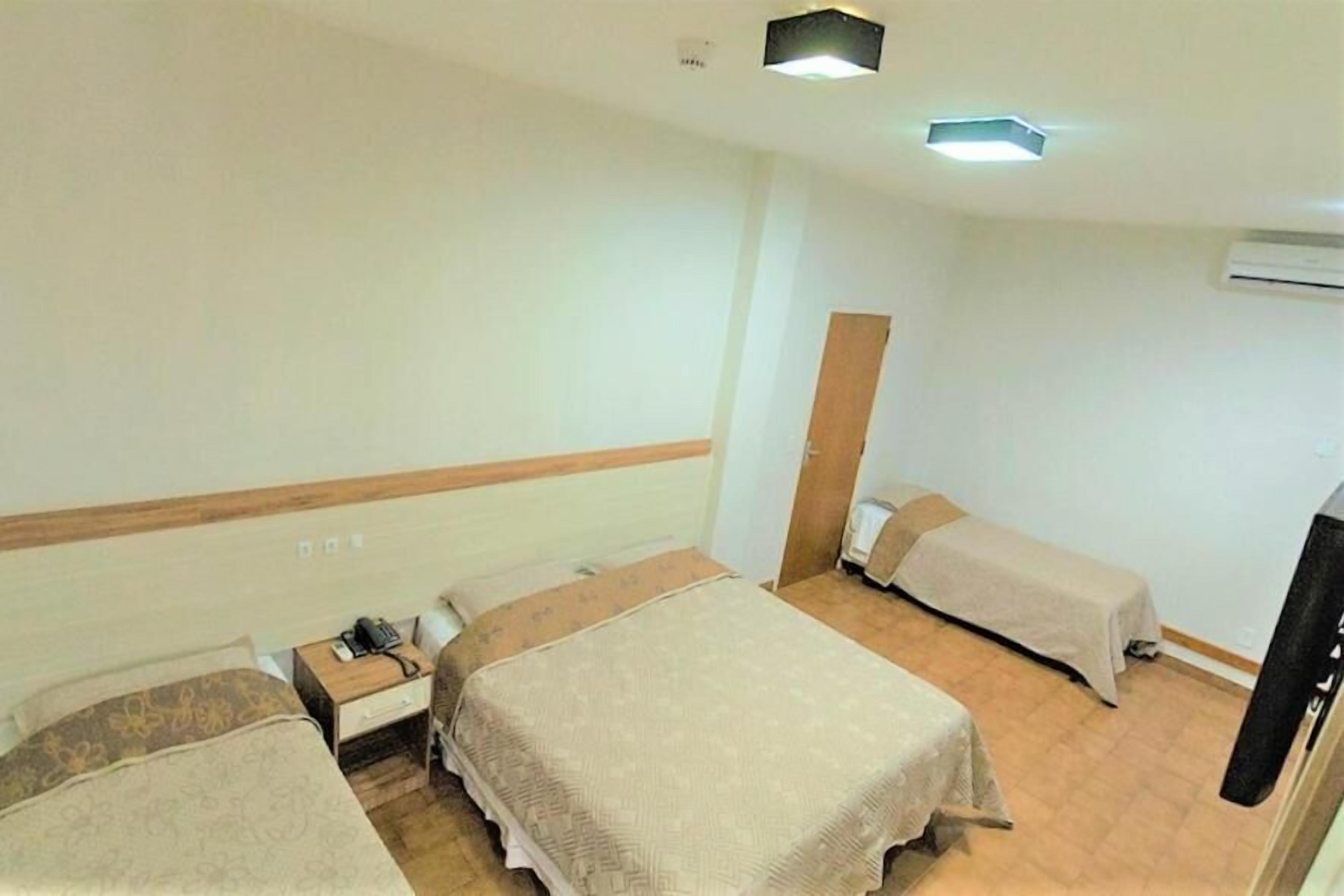 A hotel room with two single beds, a bedside table with a telephone, and a wardrobe.