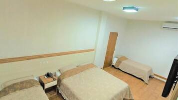 A hotel room with two single beds, a bedside table with a telephone, and a wardrobe.