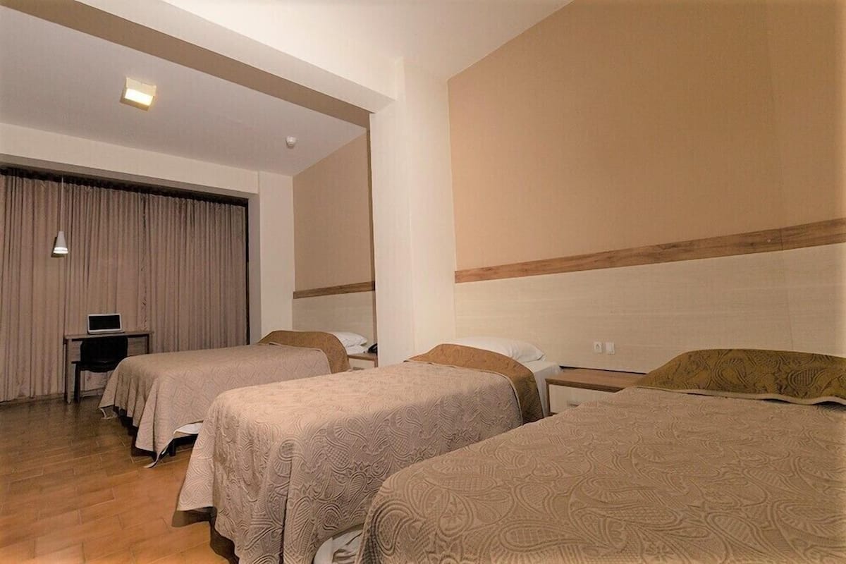 Una habitación de hotel con dos camas, un escritorio y una ventana cubierta con cortinas.