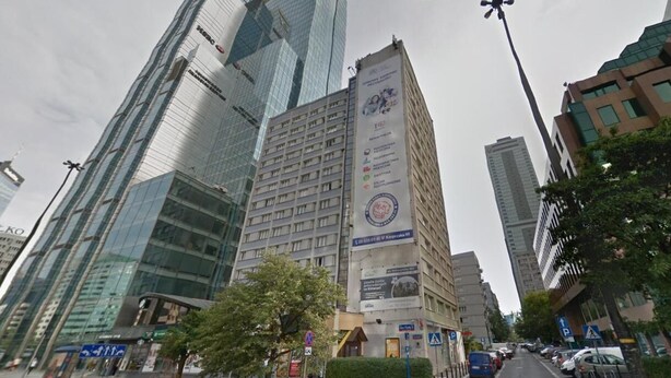 A modern urban street with high-rise buildings, including a prominent glass skyscraper and a building with a large advertisement. - Apartamenty Varsovie Sliska (Warsaw)
