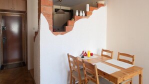 A dining area with a wooden table and chairs, a brick wall, and a kitchen in the background. - Apartamenty Varsovie Sliska (Warsaw)