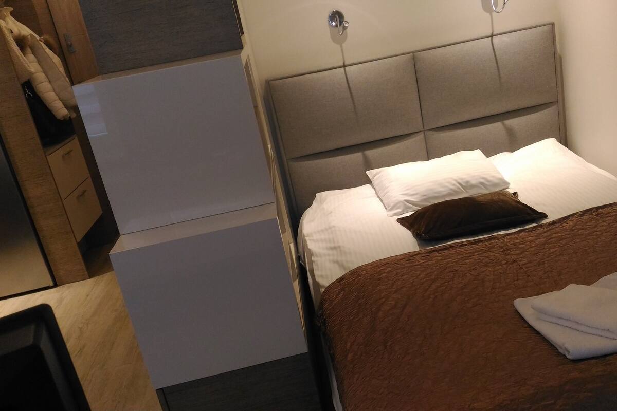 Quarto de hotel com uma cama, mesa de cabeceira e guarda-roupa.