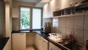 A modern kitchen with white cabinets, a microwave, a dishwasher, and a sink. - Apartamenty Varsovie Superb Panska 5 (Warsaw)