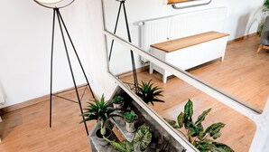 Een modern interieur met een vloerlamp, een spiegelwand, een houten bank en potplanten.