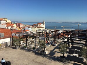 A rooftop terrace with outdoor seating and a view of the sea and cityscape.