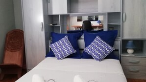 A hotel room with a bed, two pillows, a desk, and a chair. - Maison d'Architecte chez Huguette (Villalier)
