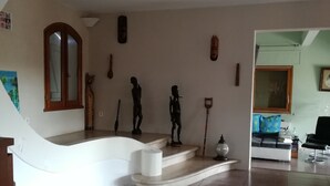 A spacious living area with a curved staircase, a sofa set, and various wall decorations. - Maison d'Architecte chez Huguette (Villalier)