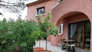 A pink building with a patio area, potted plants, and a table with chairs. - Maison d'Architecte chez Huguette (Villalier)