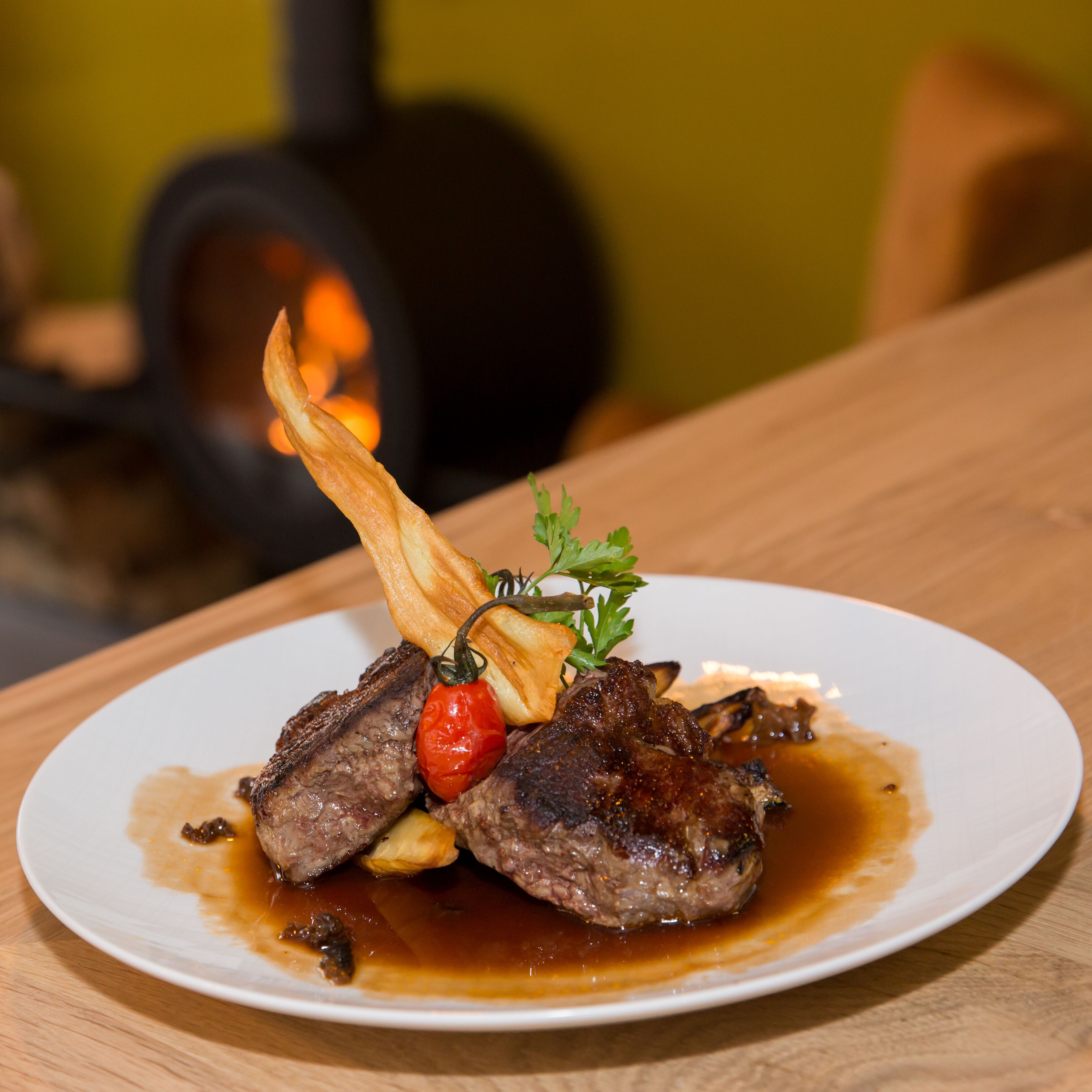 A plate of food with steak, vegetables, and sauce on a white plate.