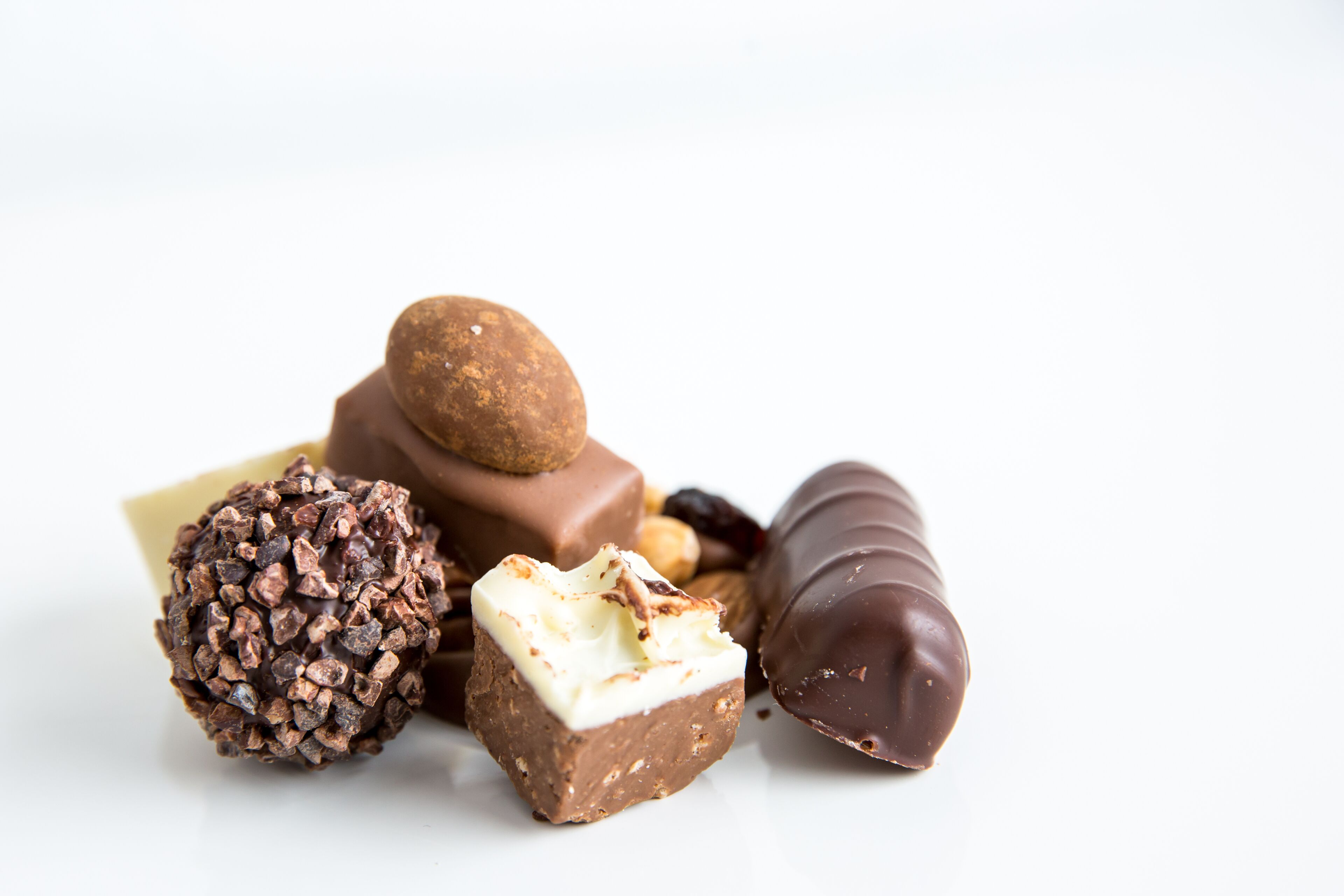 Diverse chocolade lekkernijen, waaronder een truffel, een chocolade blokje en een ronde chocolade bol.