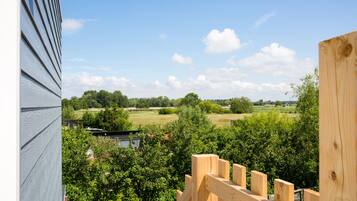 Una terraza de madera con vistas a un paisaje verde y árboles.