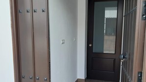 A hallway with a wooden door at the end, a light switch, and a small window.