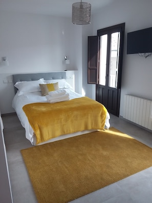 A neatly arranged bedroom with a bed, a large window, and a radiator.