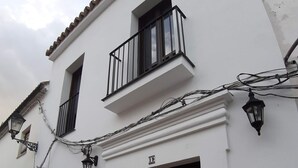 A white building with a black gate, a balcony, and a street lamp.