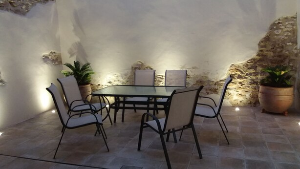 A dining area with a table and chairs, potted plants, and a stone wall.