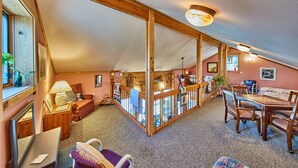 A spacious loft with a high ceiling, wooden beams, a dining area with a table and chairs, a sofa, and a balcony with a railing. - Wooded LODGE, Sleeps 9, Pet Friendly, Accessible (Ben Wheeler)