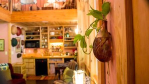 A wooden interior with a hanging plant, a kitchen area, and a dining space. - Wooded LODGE, Sleeps 9, Pet Friendly, Accessible (Ben Wheeler)