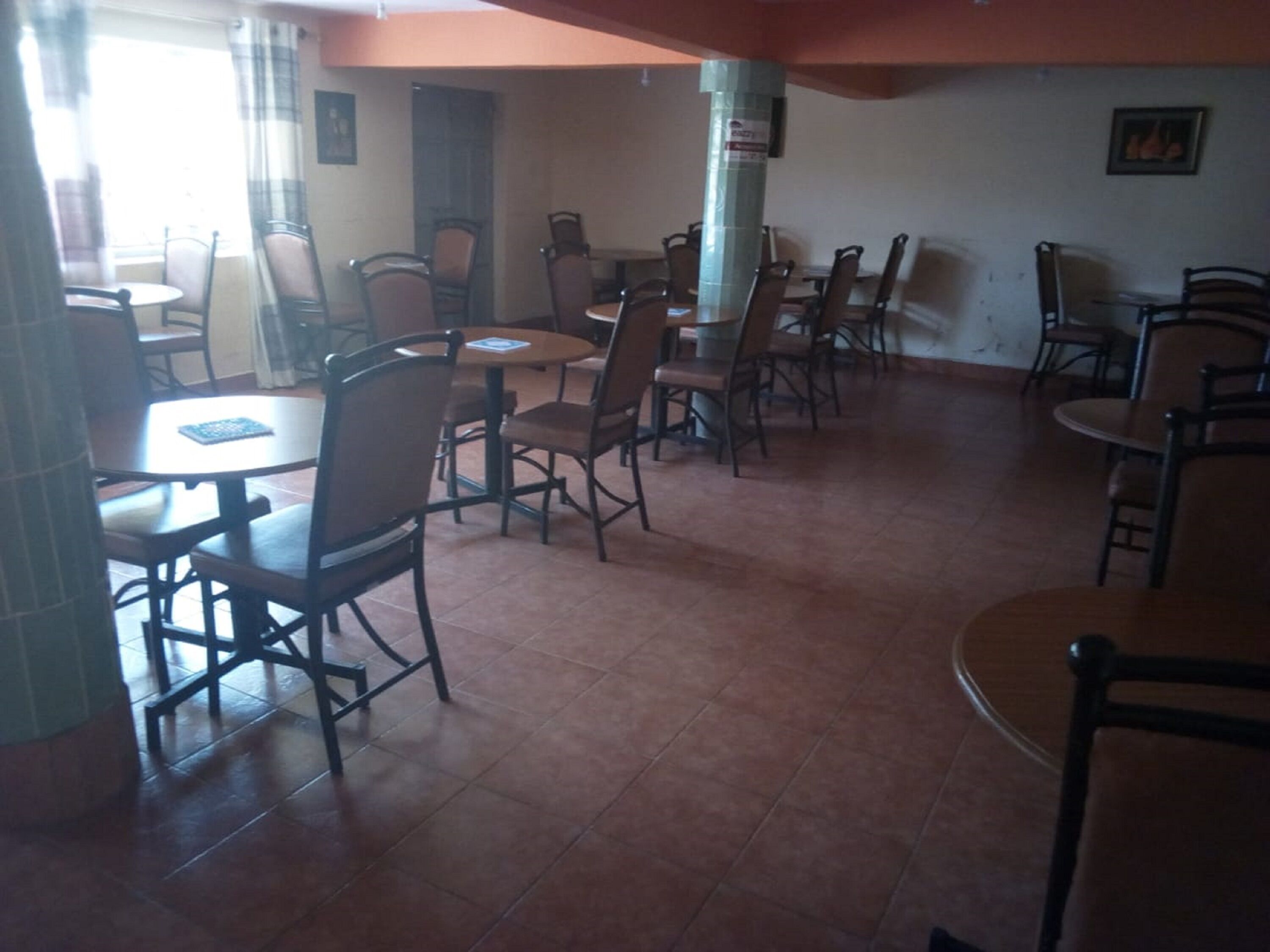 A dining area with multiple tables and chairs, a tiled floor, and a pillar.