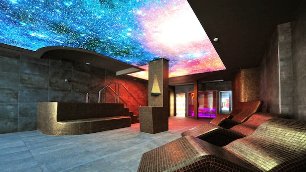 Un spa moderno con techo que simula un cielo estrellado, una zona de recepción y sillones de relax.
