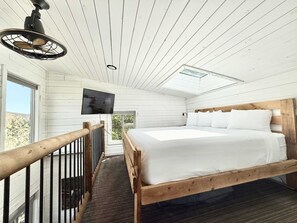 A bedroom with a bed, a TV, a skylight, and a balcony with a railing. - Treetop Cabin Stargazing w/ New Resort Pool (Orderville)