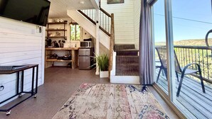 A spacious living area with a kitchen, a staircase, and a balcony with a view.