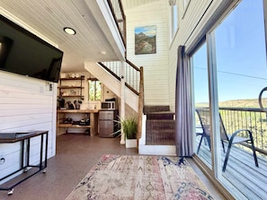 Amplia sala de estar con cocina, una escalera y un balcón con vistas.