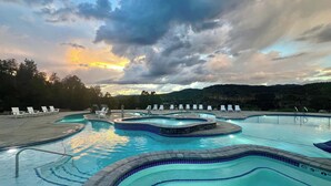 A multi-level swimming pool with lounge chairs and a mountainous backdrop.