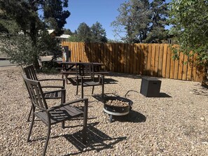 An outdoor patio with a wooden table, chairs, and a fire pit. - Treetop Cabin Stargazing w/ New Resort Pool (Orderville)