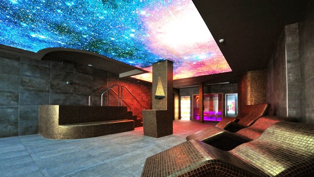 Un spa moderne doté d’un plafond représentant un ciel étoilé, d’un espace d’accueil et de chaises longues pour se détendre.