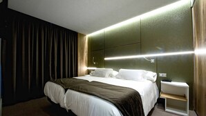 Une chambre d’hôtel moderne dotée d’un grand lit, d’une table de chevet et d’une tête de lit avec éclairage intégré.