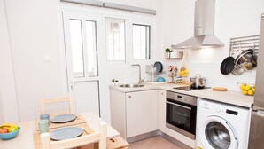 A compact kitchen with a dining area, a washing machine, and a sink. - Cozy Studio Athens Downtown - Sleeps 3 (Athens)