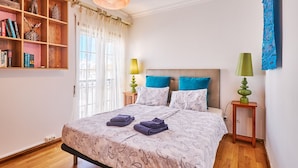 A bedroom with a bed, two bedside tables, a bookshelf, and a window with sheer curtains. - Apartment Meerlust with fantastic sea view and large balcony and garage (Armacao de Pera)