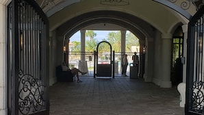 Une entrée en arc surmontée d’un sol en briques, qui mène à une zone délimitée par une grille.