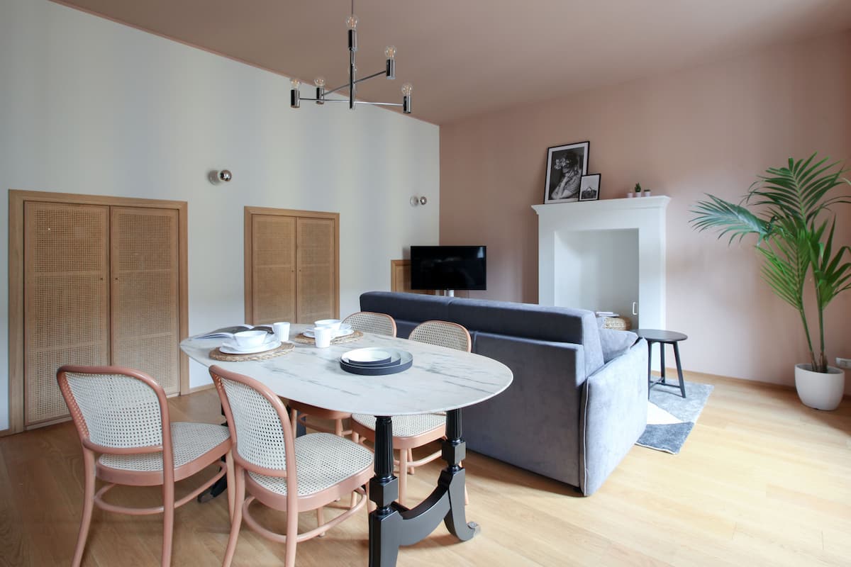 Ein modernes Wohnzimmer mit Esstisch, Stühlen, einer Couch, einem Fernseher und einem Kamin.