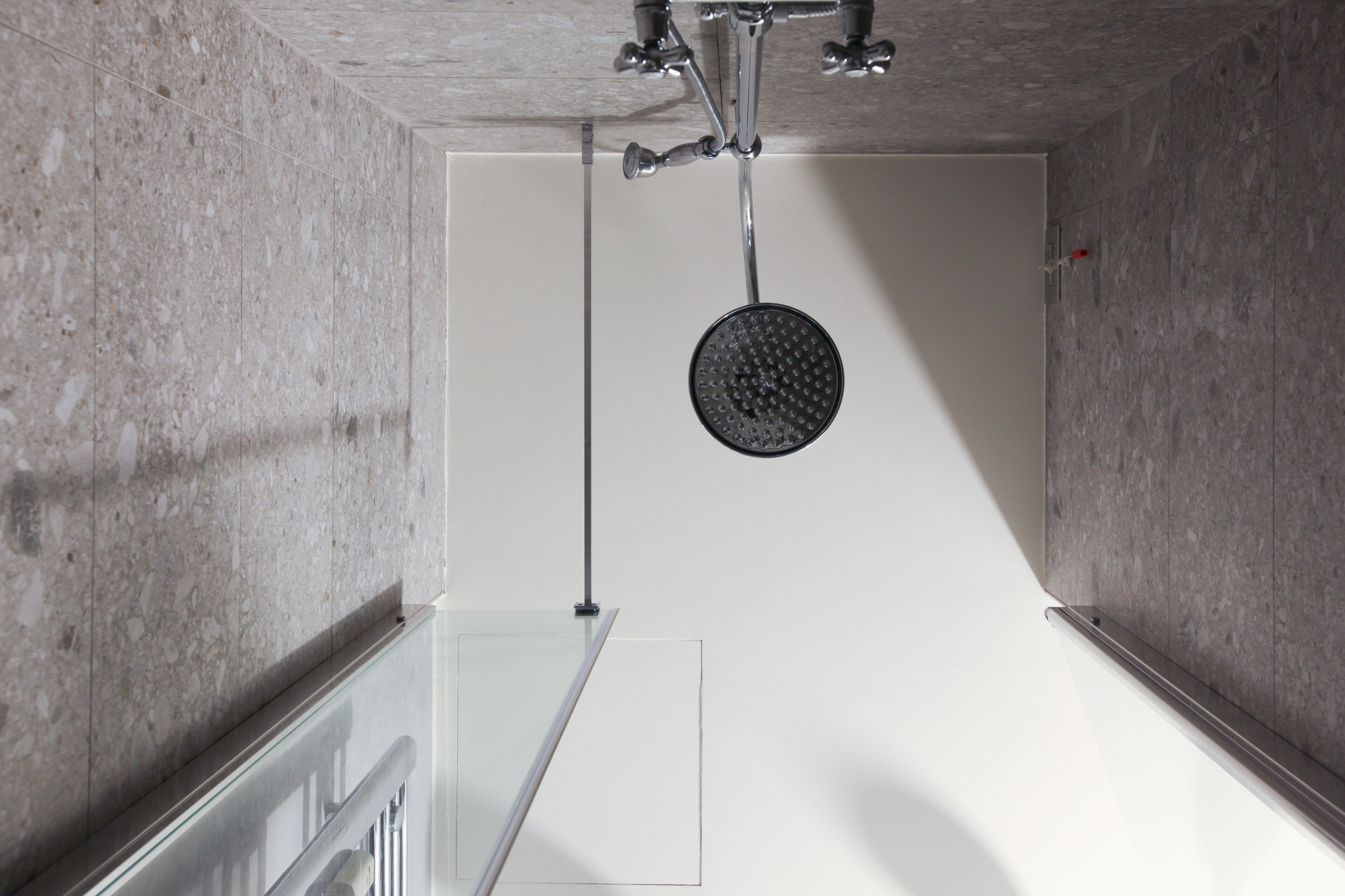 Un baño moderno con cabina de ducha de vidrio, paredes de mármol y ducha a la vista.