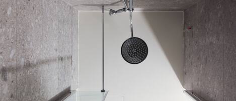 Un baño moderno con cabina de ducha de vidrio, paredes de mármol y ducha a la vista.