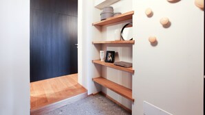 A modern hallway with wooden flooring, a dark door, and built-in shelves with various items. - Cà Bèla - Vitruvio (Milan)