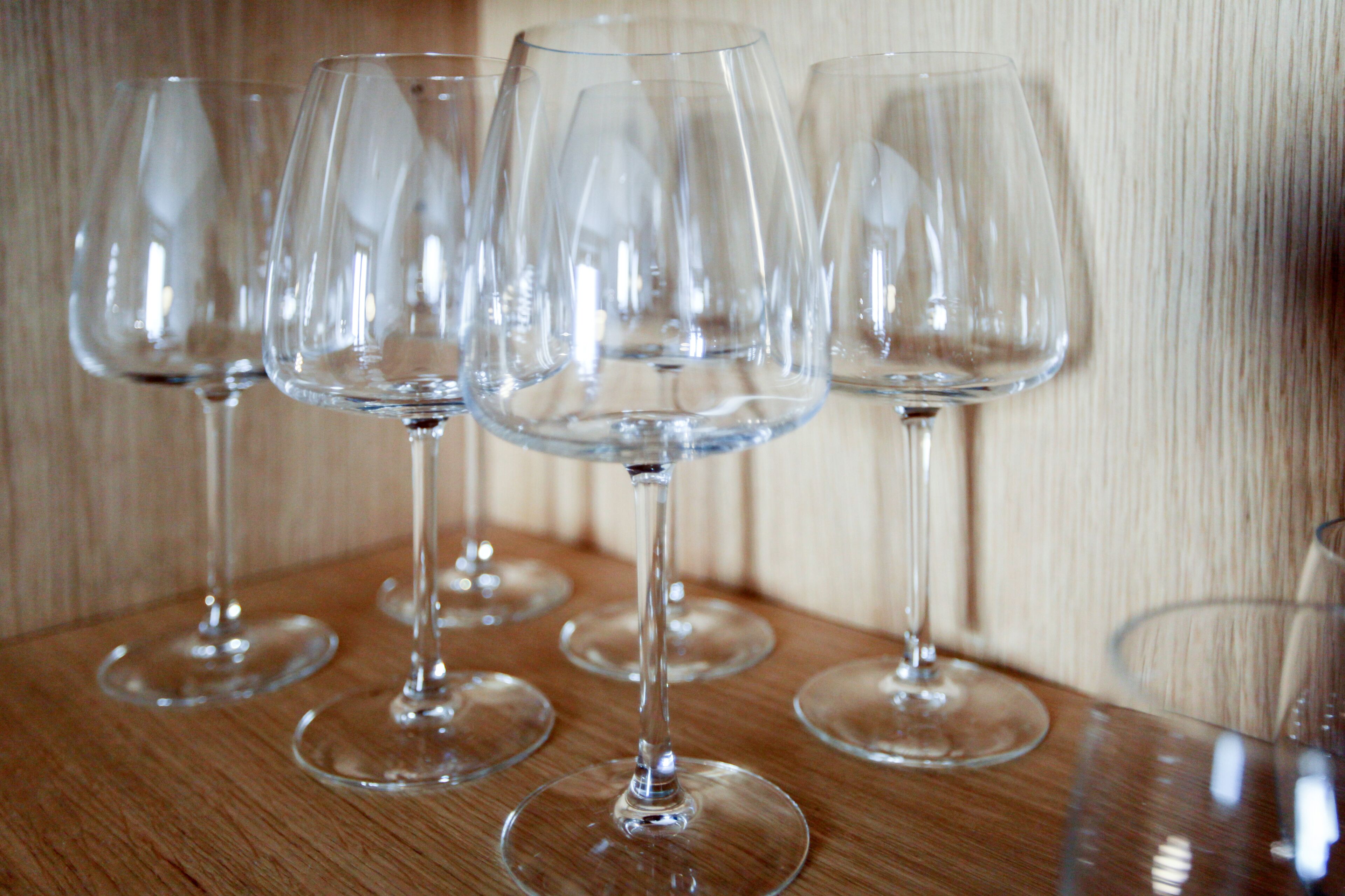 A row of empty wine glasses on a wooden surface.