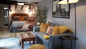 Ett modernt sovrum med en säng, en soffa, en fåtölj och en lampa.