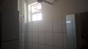 Un baño con paredes de azulejos blancos, una ventana y una lámpara en el techo.