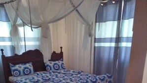 Un dormitorio con cama, cortinas y piso estampado.
