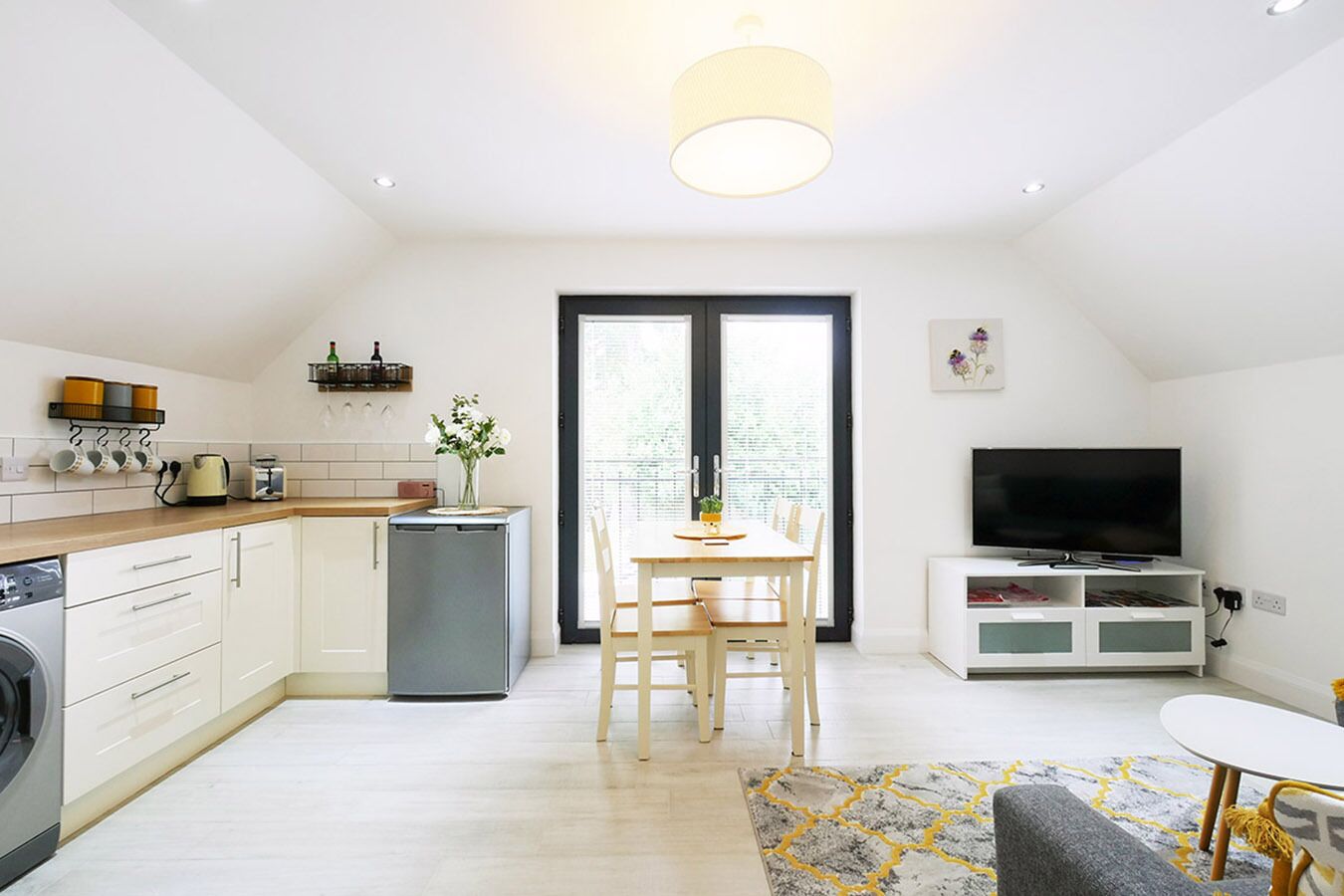 Una cocina moderna con comedor, televisor y lavadora.