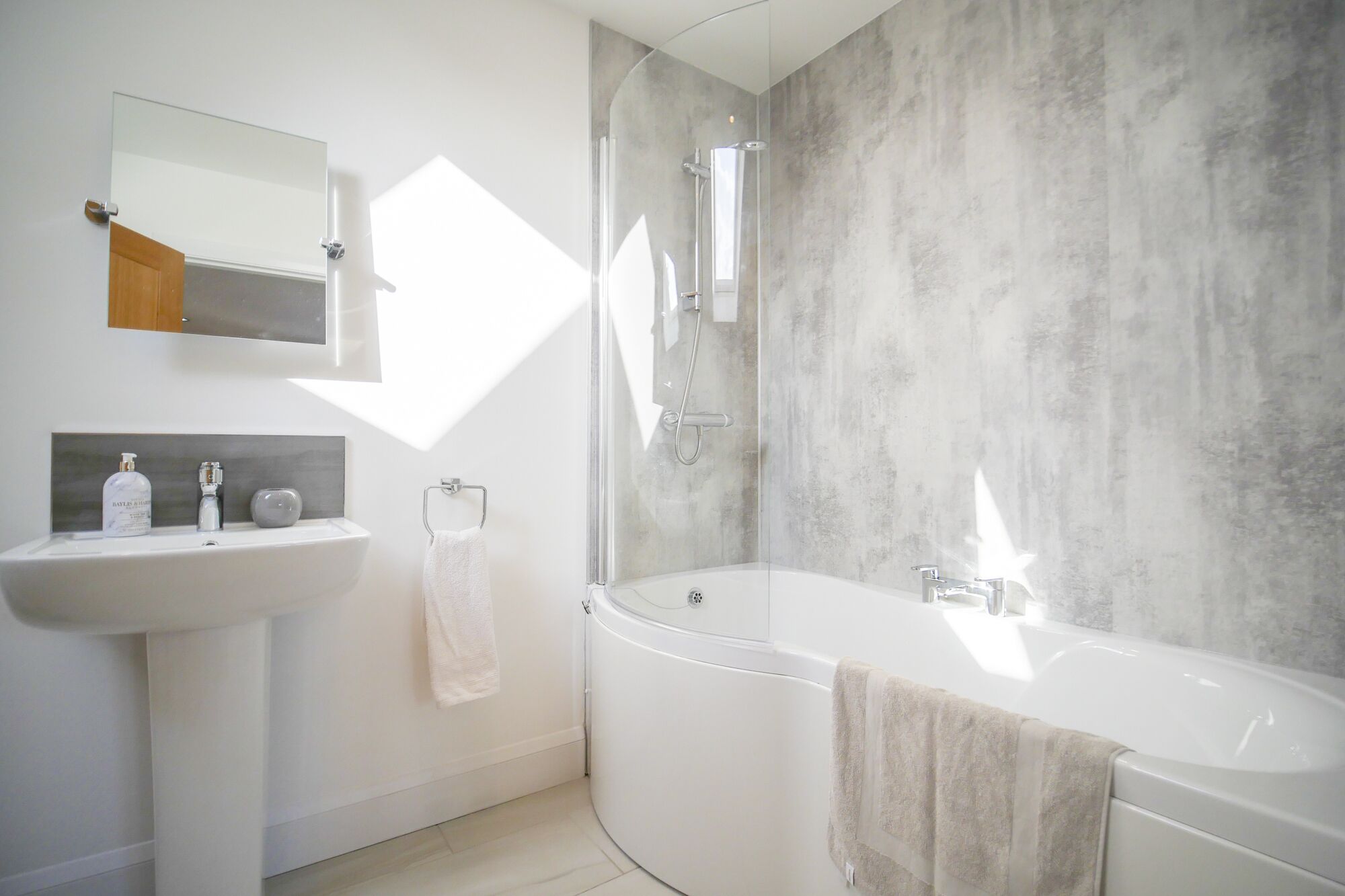 Ein modernes Badezimmer mit einer freistehenden Badewanne, einer Duschkabine und einem wandmontierten Spiegel.