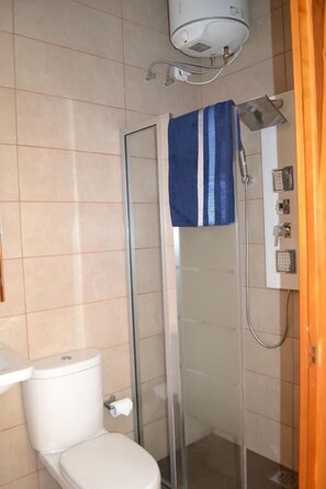 A bathroom with a toilet, a glass shower enclosure, and a towel hanging on the shower door. - La Luna Townhouse (Sliema)