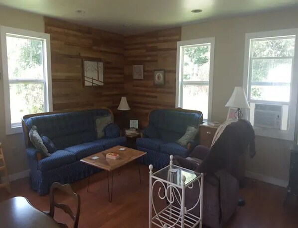 A living room with a blue sofa, a wooden wall, and a white metal stand.